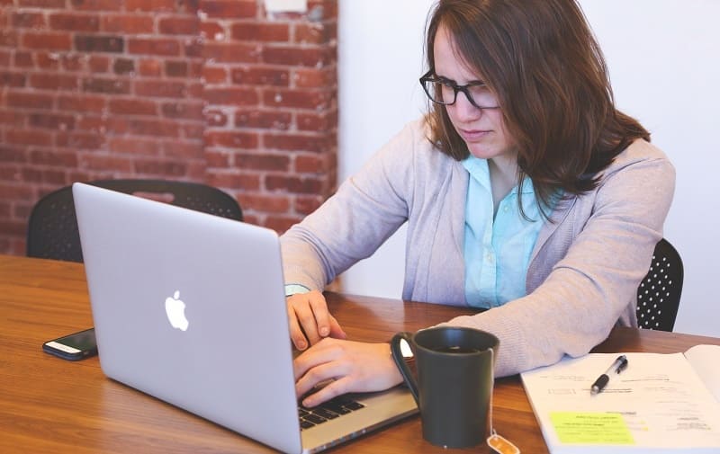 A woman sits at her laptop, looking concerned.